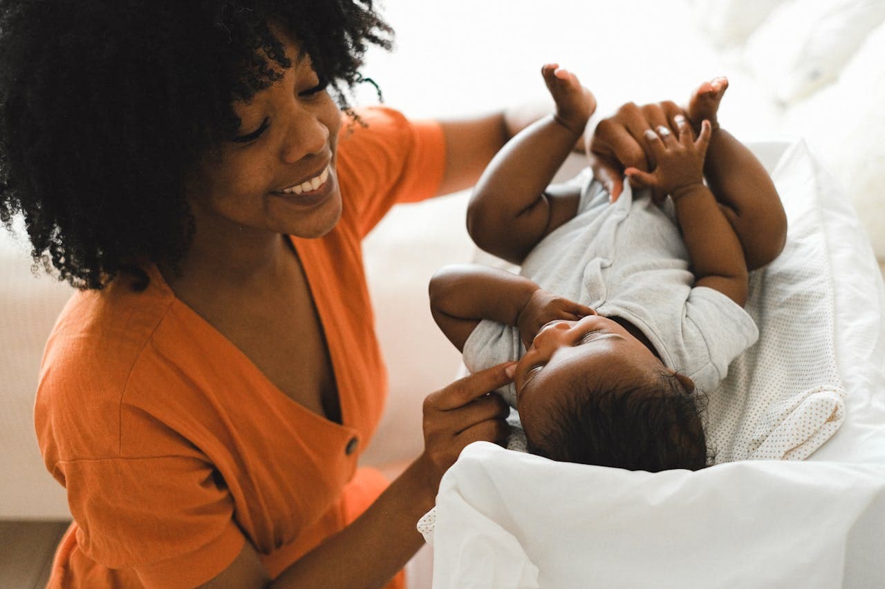 Une mère souriante jouant avec son bébé, symbolisant la protection et la transmission aux générations futures